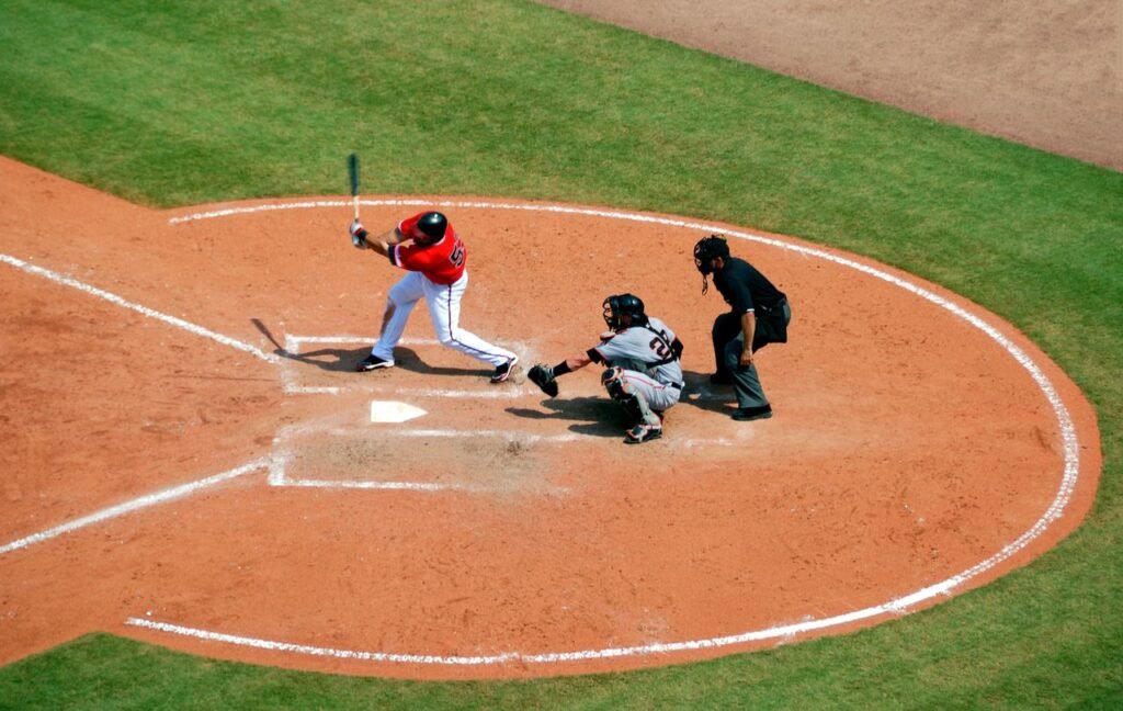 Action shot of a baseball game with batter swinging, catcher, and umpire observing play.